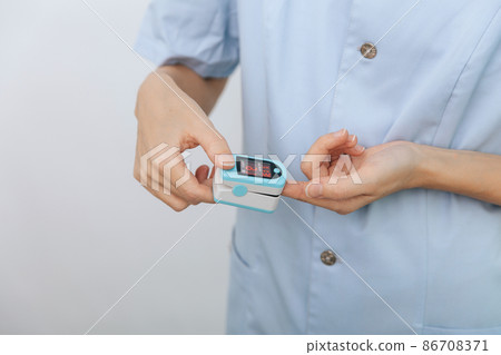 Pulse oximeter with hand of doctor isolated on white. Measuring oxygen saturation, pulse rate and oxygen levels. The concept of portable digital device to measure person's oxygen saturation. Pulse oximeter with hand of doctor isolated on white. Measuring oxygen saturation, pulse rate and oxygen levels. The concept of portable digital device to measure person's oxygen saturation. 86708371
