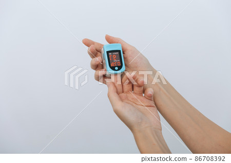 Pulse oximeter with hand of doctor isolated on white. Measuring oxygen saturation, pulse rate and oxygen levels. The concept of portable digital device to measure person's oxygen saturation. 86708392
