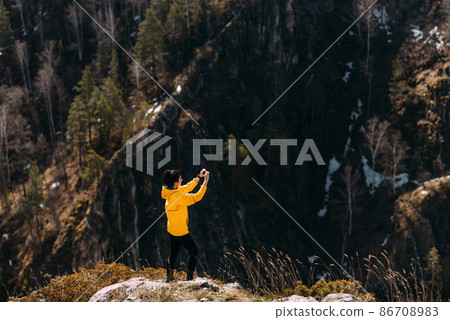 Traveler photographs nature in the mountains on the phone. Travel photographer. Take pictures on your phone. Take photos on your smartphone. Traveler in the mountains. Photo essay. Beautiful scenery 86708983