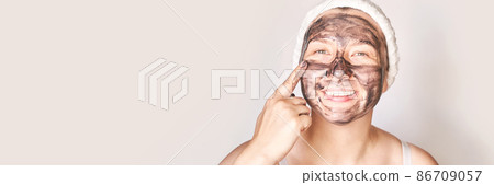 Young woman applying black face mask. Charcoal facial product. Acne and pimple Young woman applying black face mask. Charcoal facial product. Acne and pimple 86709057
