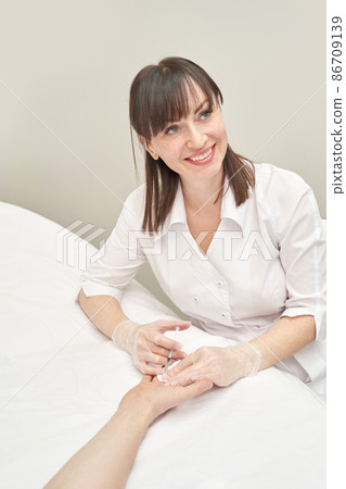 Palm injection at spa salon. Doctor hands in gloves. Closeup. Pretty patient 86709139