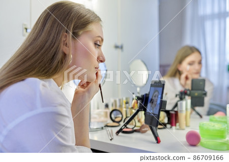 Young woman recording video, makeup beauty blog using smartphone. 86709166