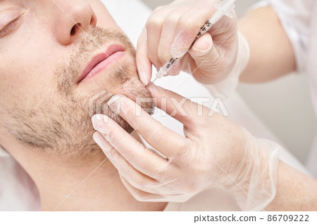 Injection at spa salon. Doctor hands in gloves. Closeup. Pretty male patient Injection at spa salon. Doctor hands in gloves. Closeup. Pretty male patient 86709222