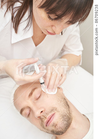 Injection at spa salon. Doctor hands in gloves. Closeup. Pretty male patient Injection at spa salon. Doctor hands in gloves. Closeup. Pretty male patient 86709238