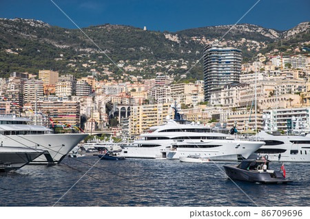 A lot of huge yachts are in port of Monaco at sunny day, megayachts are moored in marina, is a yacht show, Monte Carlo, real estate housing is on background, glossy board of the motor boat 86709696