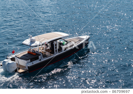 The large luxury boat on the background of blue water, port of Hercules in Monaco, sunny glare of the sun on the water, powerful boat, glossy surfaces shine in sunny weather The large luxury boat on the background of blue water, port of Hercules in Monaco, sunny glare of the sun on the water, powerful boat, glossy surfaces shine in sunny weather 86709697