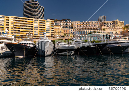 A lot of huge yachts are in port of Monaco at sunny day, megayachts are moored in marina, is a yacht show, Monte Carlo, real estate housing is on background, glossy board of the motor boat 86709698