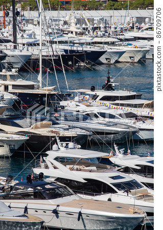 A lot of huge yachts are in port Hercule of Monaco at sunny day, Monte Carlo, many small boats are on background, interiors of motor boat, chilling zone of megayachts, sun reflections on glossy boards 86709706
