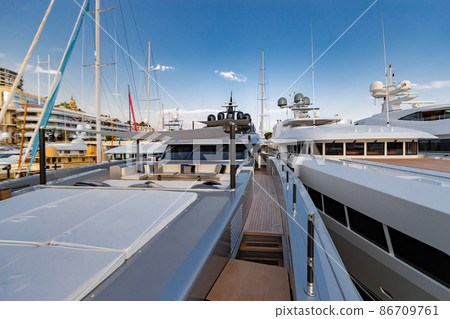 The front deck of huge yacht in port of Monaco at sunset, the place for landing of helicopter, a lot of motorboats are on background, the chrome plated handrail, megayacht is moored in marina, dusk The front deck of huge yacht in port of Monaco at sunset, the place for landing of helicopter, a lot of motorboats are on background, the chrome plated handrail, megayacht is moored in marina, dusk 86709761