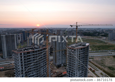 Tower cranes in action at construction site on sunset background.  Tower cranes in action at construction site on sunset background.  86710178