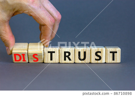 Distrust or trust symbol. Businessman turns wooden cubes, changes words 'distrust' to 'trust'. Beautiful grey table, grey background. Business and distrust or trust concept, copy space. Distrust or trust symbol. Businessman turns wooden cubes, changes words 'distrust' to 'trust'. Beautiful grey table, grey background. Business and distrust or trust concept, copy space. 86710898