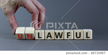 Lawful or unlawful symbol. Businessman turns wooden cubes and changes the word unlawful to lawful. Beautiful grey table, grey background, copy space. Business and lawful or unlawful concept. Lawful or unlawful symbol. Businessman turns wooden cubes and changes the word unlawful to lawful. Beautiful grey table, grey background, copy space. Business and lawful or unlawful concept. 86710907