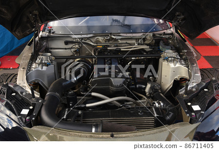 Sports car engine with turbine. An open race car hood on a pit stop while racing 86711405