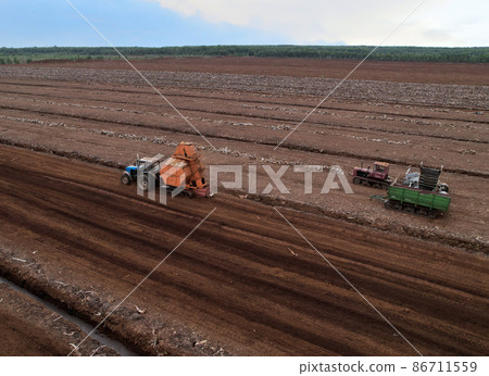 Peat extraction site. Harvester at collecting peat on peatlands. Mining and harvesting Peat extraction site. Harvester at collecting peat on peatlands. Mining and harvesting 86711559