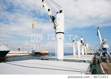 The shipyard never sleeps. A photo of a harbor with anchored ships with cranes. 86711911