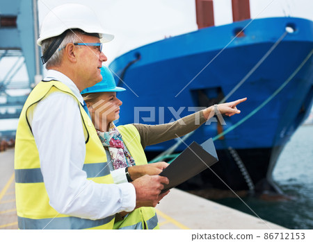 Ship hunt. Two dock workers conferring among themselves while surveying the harbor. Ship hunt. Two dock workers conferring among themselves while surveying the harbor. 86712153