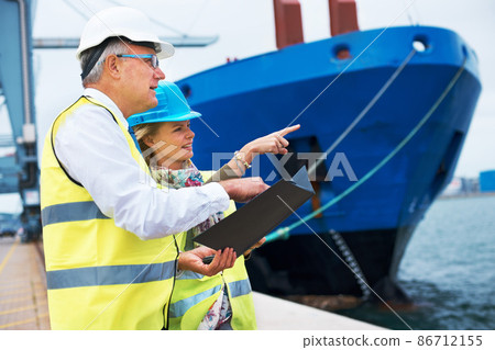 Looking out for the right ship. Two dock workers conferring among themselves while surveying the harbor. 86712155