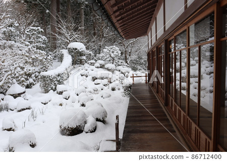 一棟寬邊日本房屋的景觀，玻璃窗映照出樹木山中的雪花園 86712400