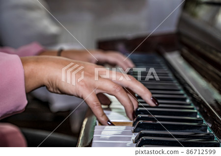 Close-up of female hands on the piano keyboard. playing piano while with both hands 86712599