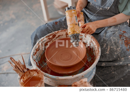 Young potter makes ceramic dish in art studio 86715480