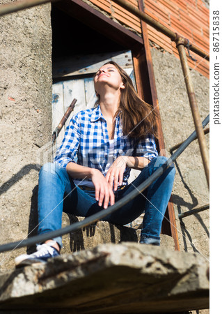 Slender positive woman posing on the porch in farm yard 86715838