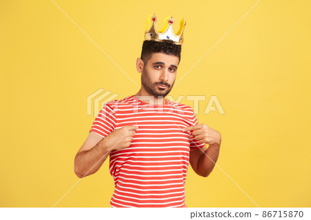 I'm king. Ambitious bearded man wearing golden crown and pointing himself, looking with arrogance, declaring his authority, superior privileged status. Indoor studio shot isolated on yellow background I'm king. Ambitious bearded man wearing golden crown and pointing himself, looking with arrogance, declaring his authority, superior privileged status. Indoor studio shot isolated on yellow background 86715870