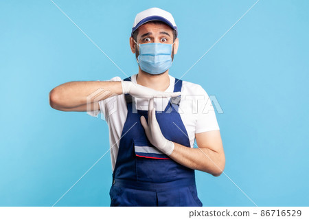 Overworked handyman in overalls, mask and gloves showing time out gesture, need break. Profession of service industry, courier delivery, housekeeping maintenance. Worker in uniform gesturing stop. Overworked handyman in overalls, mask and gloves showing time out gesture, need break. Profession of service industry, courier delivery, housekeeping maintenance. Worker in uniform gesturing stop. 86716529