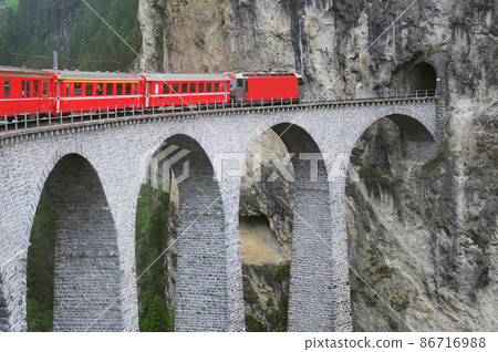 Passenger train goes from Chur to St. Moritz on Landwasser viaduct. 86716988