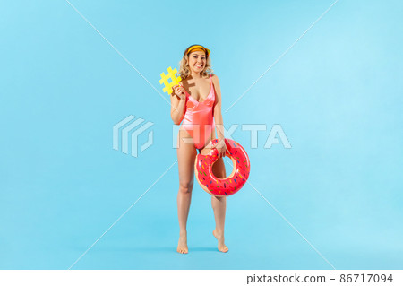 Full length beautiful tourist woman in swimsuit holding rubber ring and hashtag symbol, viral web message, famous blog about summer trip to tropical beach. studio shot isolated on blue background Full length beautiful tourist woman in swimsuit holding rubber ring and hashtag symbol, viral web message, famous blog about summer trip to tropical beach. studio shot isolated on blue background 86717094