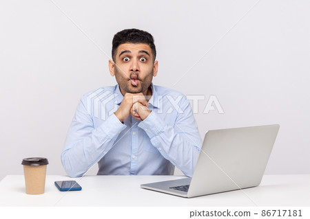 Funny comical amazed man employee sitting office workplace with laptop, making humorous fish face with big eyes and surprised shocked expression . indoor studio shot isolated on white background Funny comical amazed man employee sitting office workplace with laptop, making humorous fish face with big eyes and surprised shocked expression . indoor studio shot isolated on white background 86717181