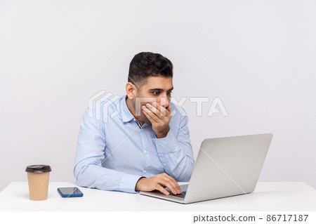 I won't tell anything. Frightened man employee sitting office workplace, covering mouth looking terrified at laptop screen, talking video call or found scary secret on internet. studio shot isolated I won't tell anything. Frightened man employee sitting office workplace, covering mouth looking terrified at laptop screen, talking video call or found scary secret on internet. studio shot isolated 86717187