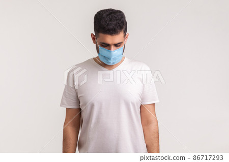 Sick man in hygienic mask looking down sadly, scared and desperate about coronavirus infection, airborne respiratory illness such as flu, 2019-nCoV, ebola. studio shot isolated on white background 86717293