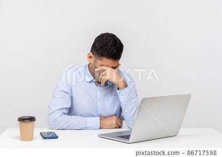 Upset man employee sitting office workplace with laptop on desk, bowing head and crying, feeling depressed, worried about problems at work, lost job. indoor studio shot isolated on white background 86717598