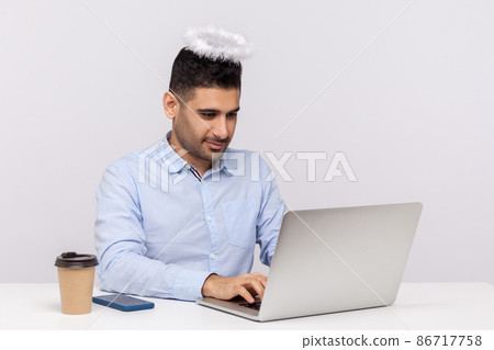 Diligent office worker or top manager sitting at workplace with saint angelic halo on head, working hard attentive on laptop, he has title of best employee. studio shot isolated on white background Diligent office worker or top manager sitting at workplace with saint angelic halo on head, working hard attentive on laptop, he has title of best employee. studio shot isolated on white background 86717758