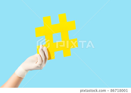 Closeup hand in hygienic gloves holding hashtag symbol, viral tagged message about coronavirus epidemic, internet tips to wear protection, hash sign on forum blogs to stay safe on covid-19 quarantine 86718001