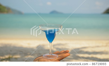 Man hands shake blue cocktails in glasses on beach 86719093