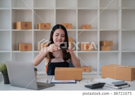 Asian Business owner confirm address to send to customer orders talking by cell phone before pack products. Successful SME entrepreneur concept. Asian Business owner confirm address to send to customer orders talking by cell phone before pack products. Successful SME entrepreneur concept. 86721075
