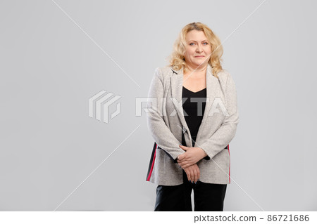 Portrait of positive senior woman in leather trousers and blazer over grey studio background Portrait of positive senior woman in leather trousers and blazer over grey studio background 86721686