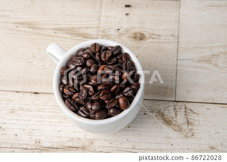 Arabica and Robusta roasted coffee beans in white glass on wooden background cutout Arabica and Robusta roasted coffee beans in white glass on wooden background cutout 86722028