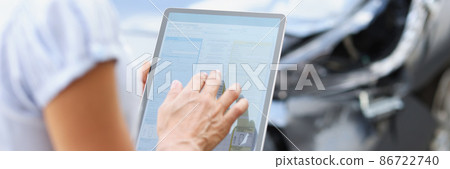 agent driver filling out insurance claim on digital tablet against background of broken car closeup 86722740