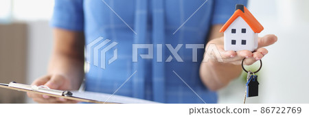 Woman holding toy house with keys and documents on clipboard closeup 86722769