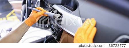Master cleans ventilation system in car with brush closeup 86722777