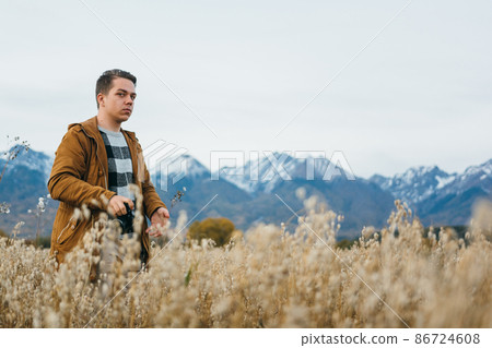 The man is a photographer in the field takes a picture on an old retro film camera. The man is a photographer in the field takes a picture on an old retro film camera. 86724608