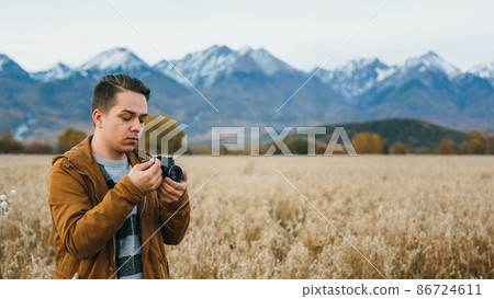 The man is a photographer in the field takes a picture on an old retro film camera. The man is a photographer in the field takes a picture on an old retro film camera. 86724611