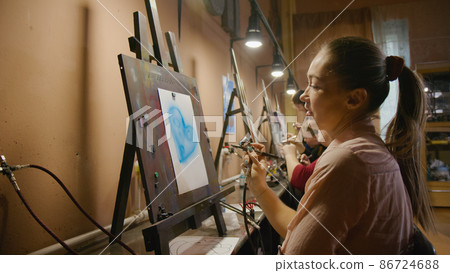 Woman artist learns to paint with airbrush with acrylic dye, paper and easel. Concept modern art, airbrushing, aerography, graffiti, aerosol spray Woman artist learns to paint with airbrush with acrylic dye, paper and easel. Concept modern art, airbrushing, aerography, graffiti, aerosol spray 86724688