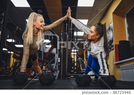 Sporty women giving high five to each other while working out together at gym. 86725948