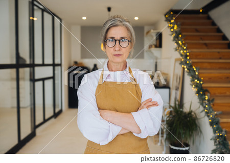 Portrait of strict granny standing in displeased pose staring angry at camera Portrait of strict granny standing in displeased pose staring angry at camera 86726820