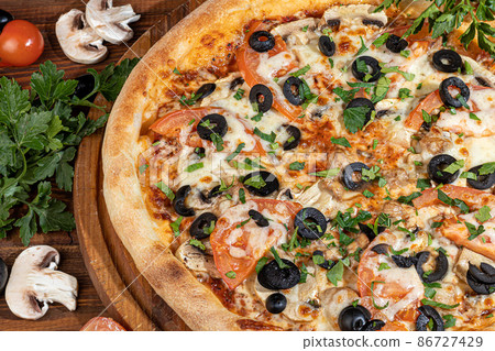 Pizza calzone with bacon and cheese, herbs and cherry tomatoes. With mozzarella, shrimps and octopuses, mussels and other products on a wooden background. Pizza calzone with bacon and cheese, herbs and cherry tomatoes. With mozzarella, shrimps and octopuses, mussels and other products on a wooden background. 86727429