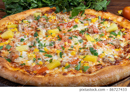 Pizza calzone with bacon and cheese, herbs and cherry tomatoes. With mozzarella, shrimps and octopuses, mussels and other products on a wooden background. 86727433