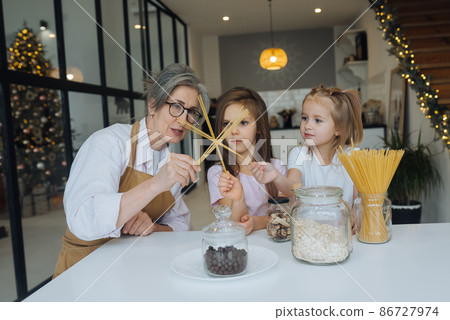 Grandmother and granddaughter are cooking on kitchen. Grandmother and granddaughter are cooking on kitchen. 86727974
